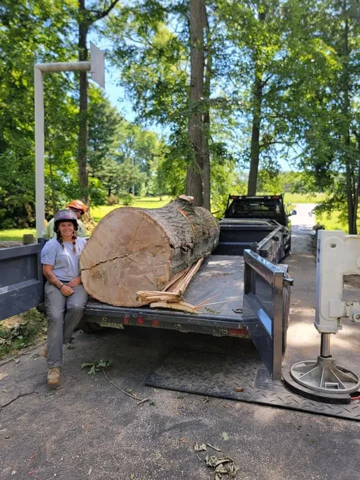A Ghost Tree Service crew member beside a freshly cut log section